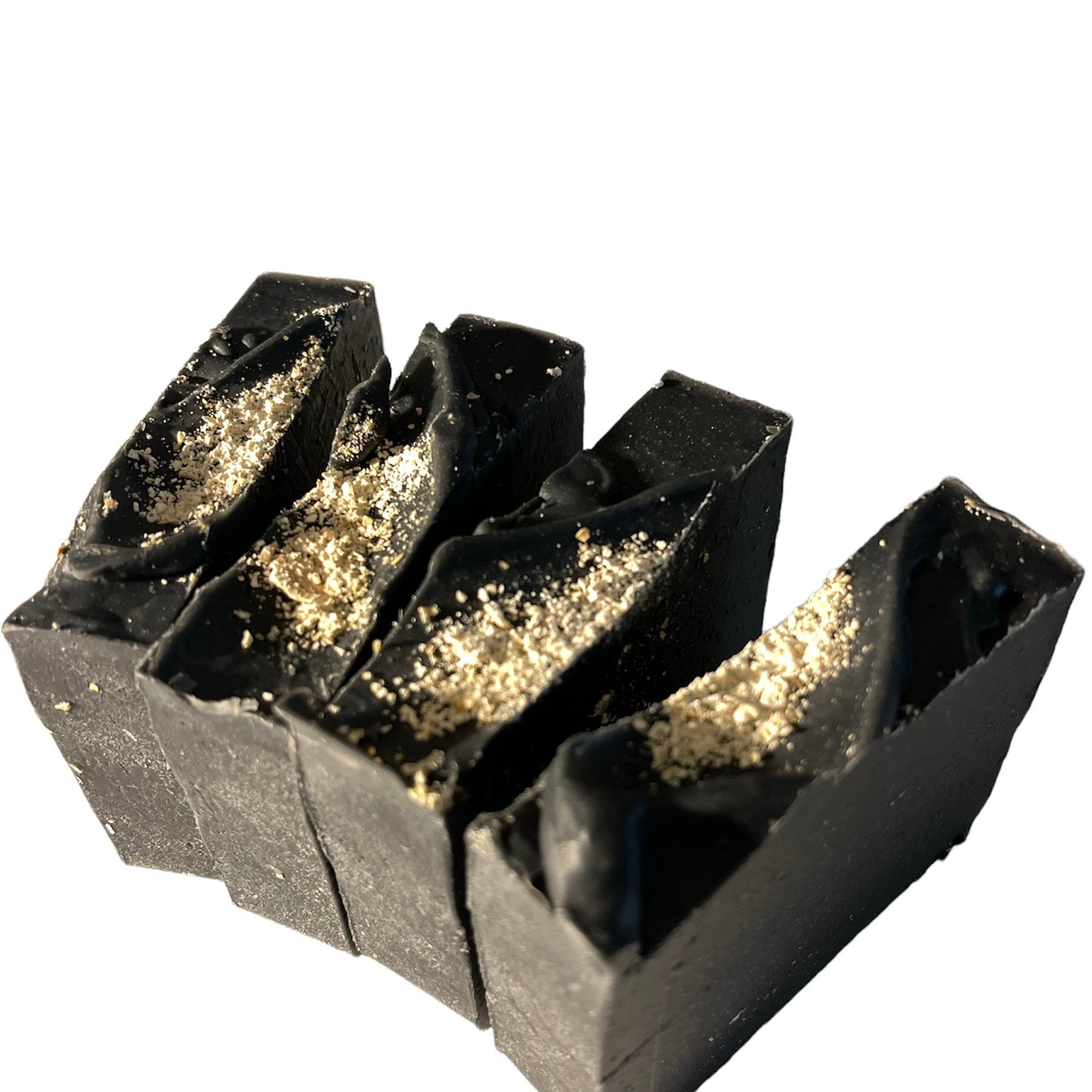Black soap bars with speckled topping, rough texture, and angled cut edges
