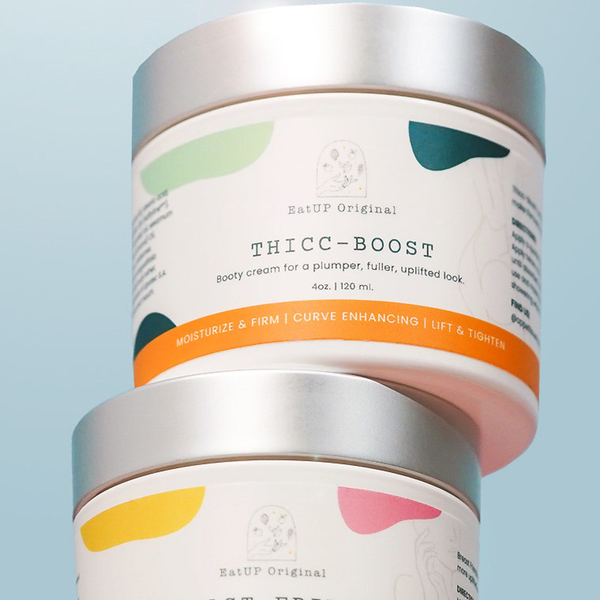 Booty cream jars with silver lids, white labels, and colorful accents EatUP Original brand
