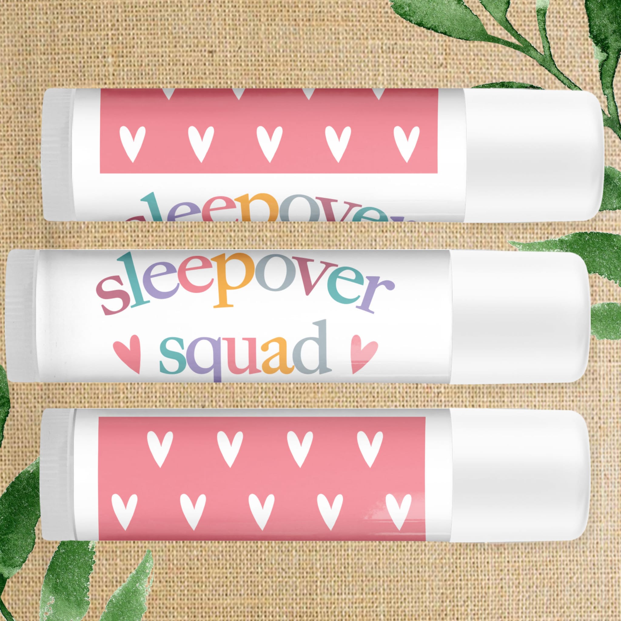 Lip balm tubes with pink heart pattern and "sleepover" text, white plastic container