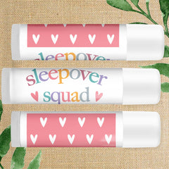 Lip balm tubes with pink heart pattern and "sleepover" text, white plastic container