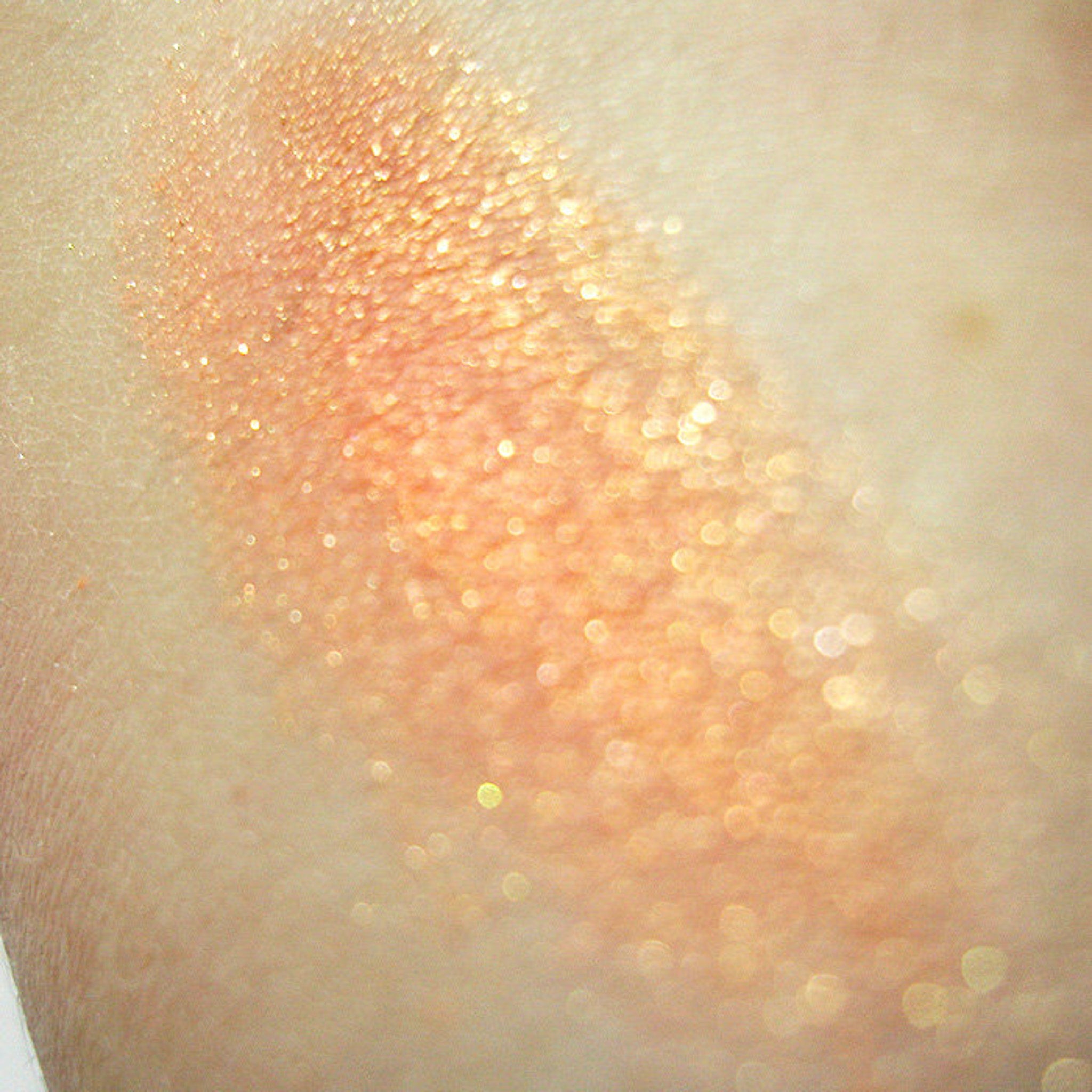 Close-up of peach mineral eye shadow with soft shimmer and finely milled powder texture in compact pan