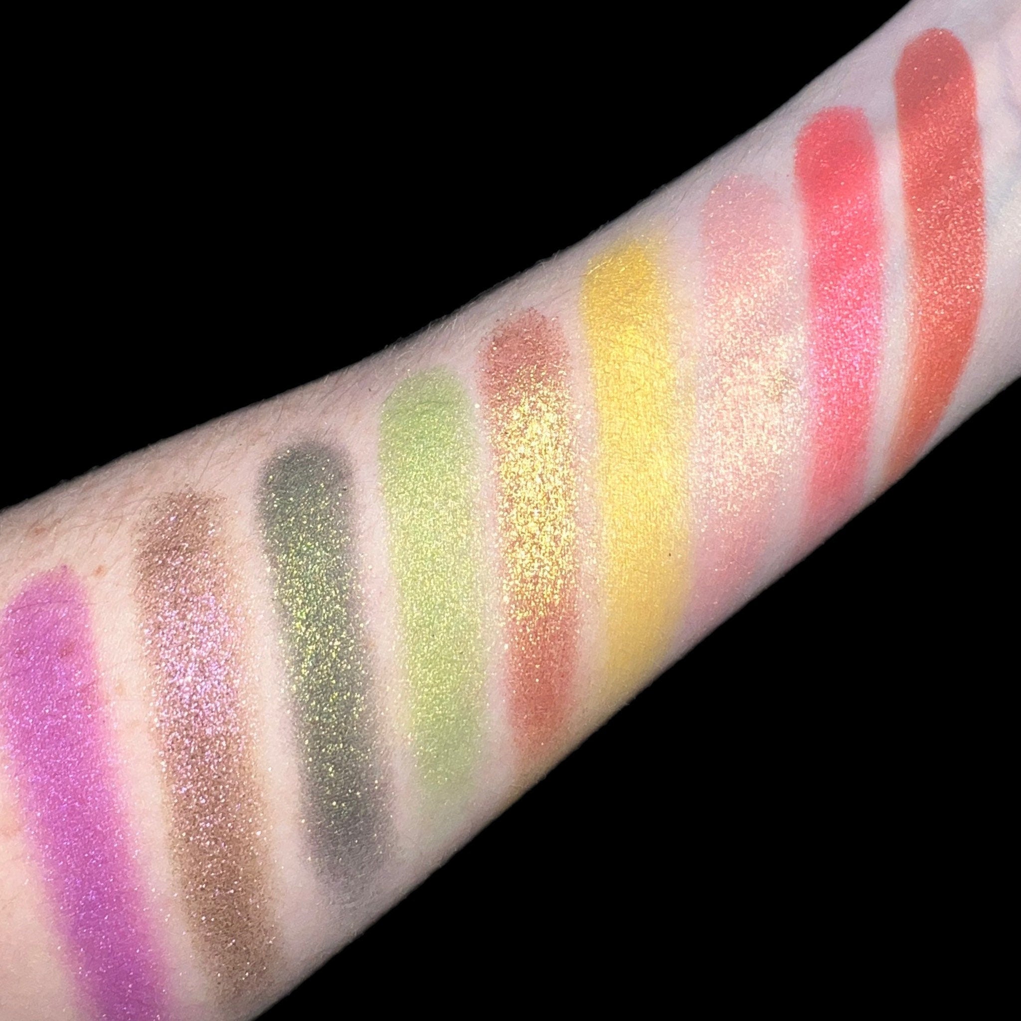 Eyeshadow swatches with various colors including pink, green, yellow, and orange on skin, showing glitter finish