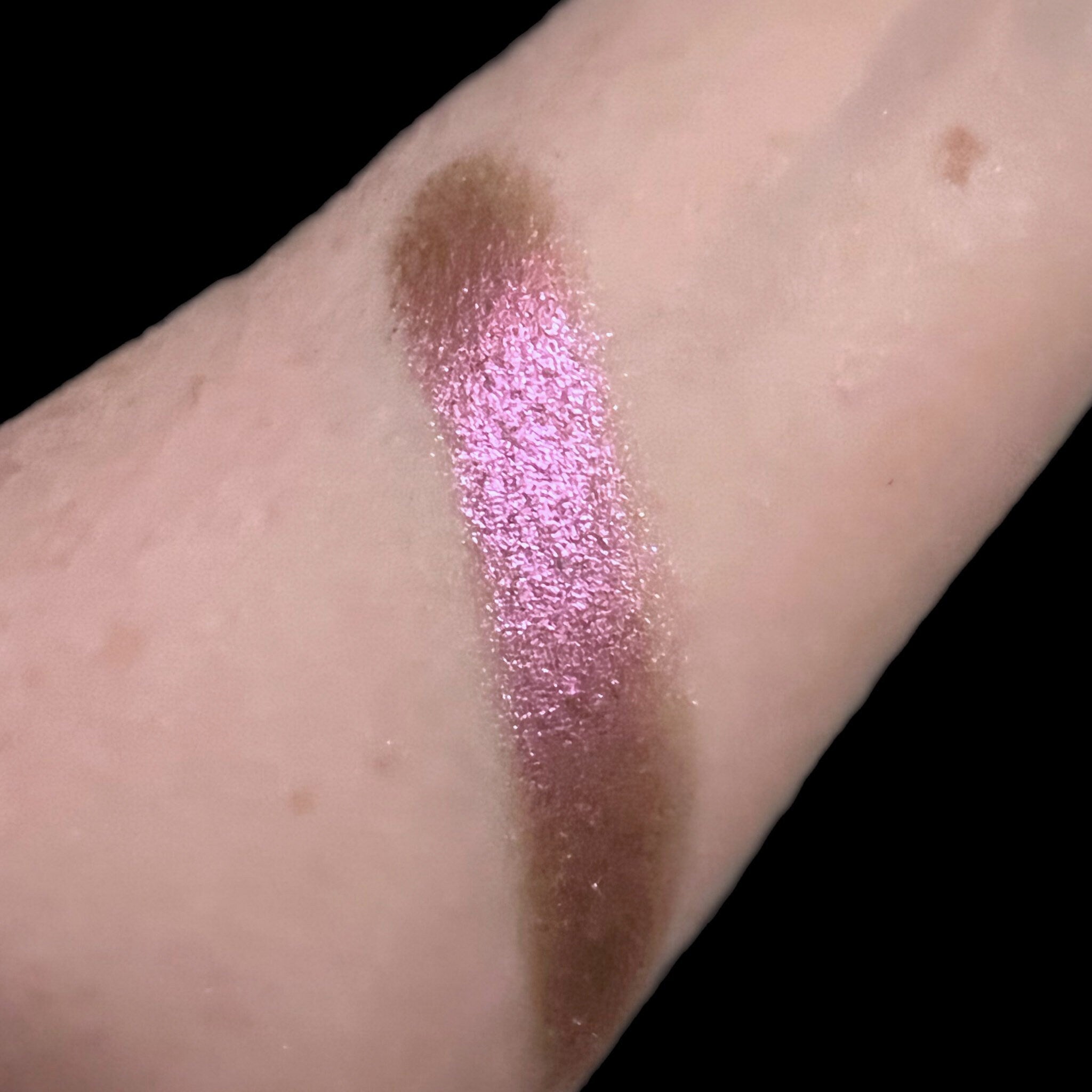Close-up of a hand applying Fox Grape eyeshadow with a blending brush, showing smooth pigment build-up on eyelid.