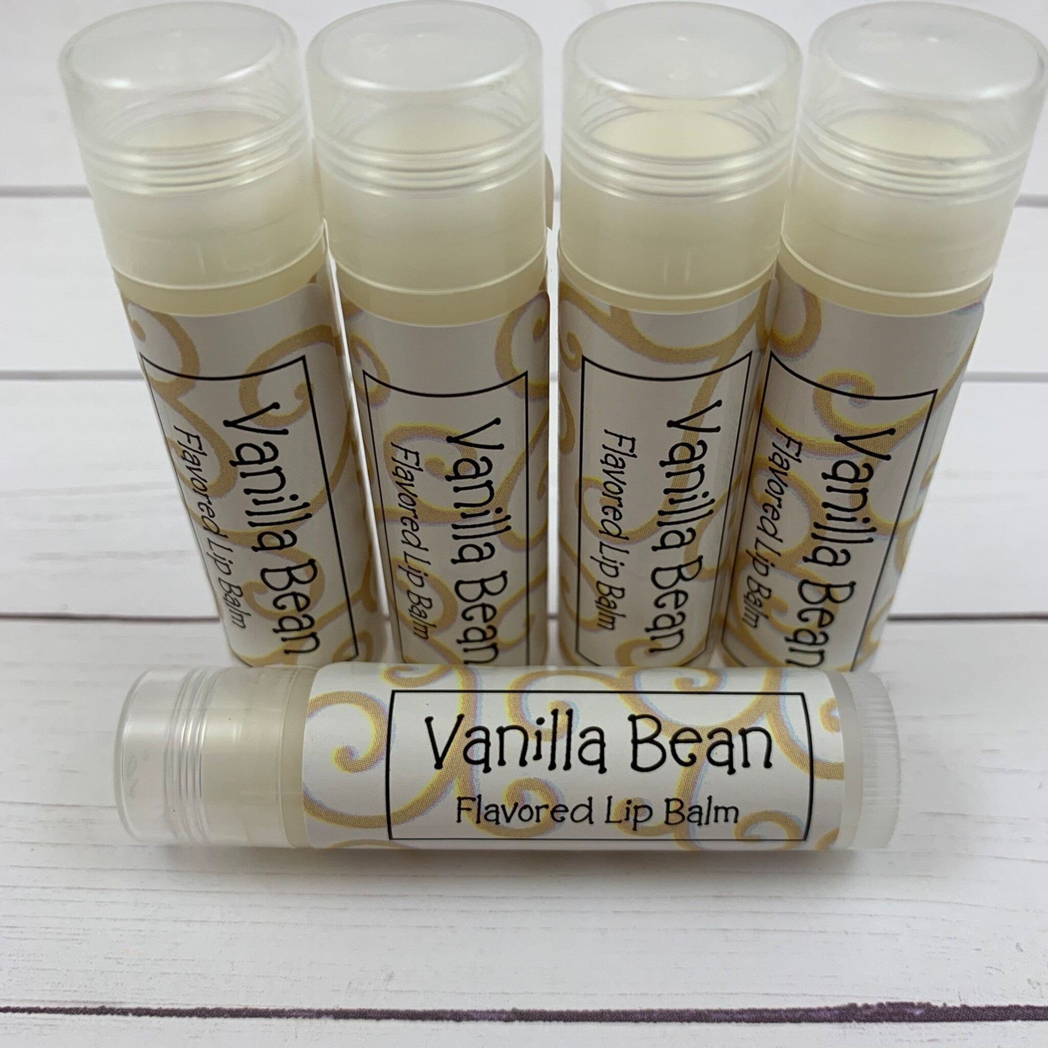 Lip balm tubes with clear, white, and gold label, product name visible