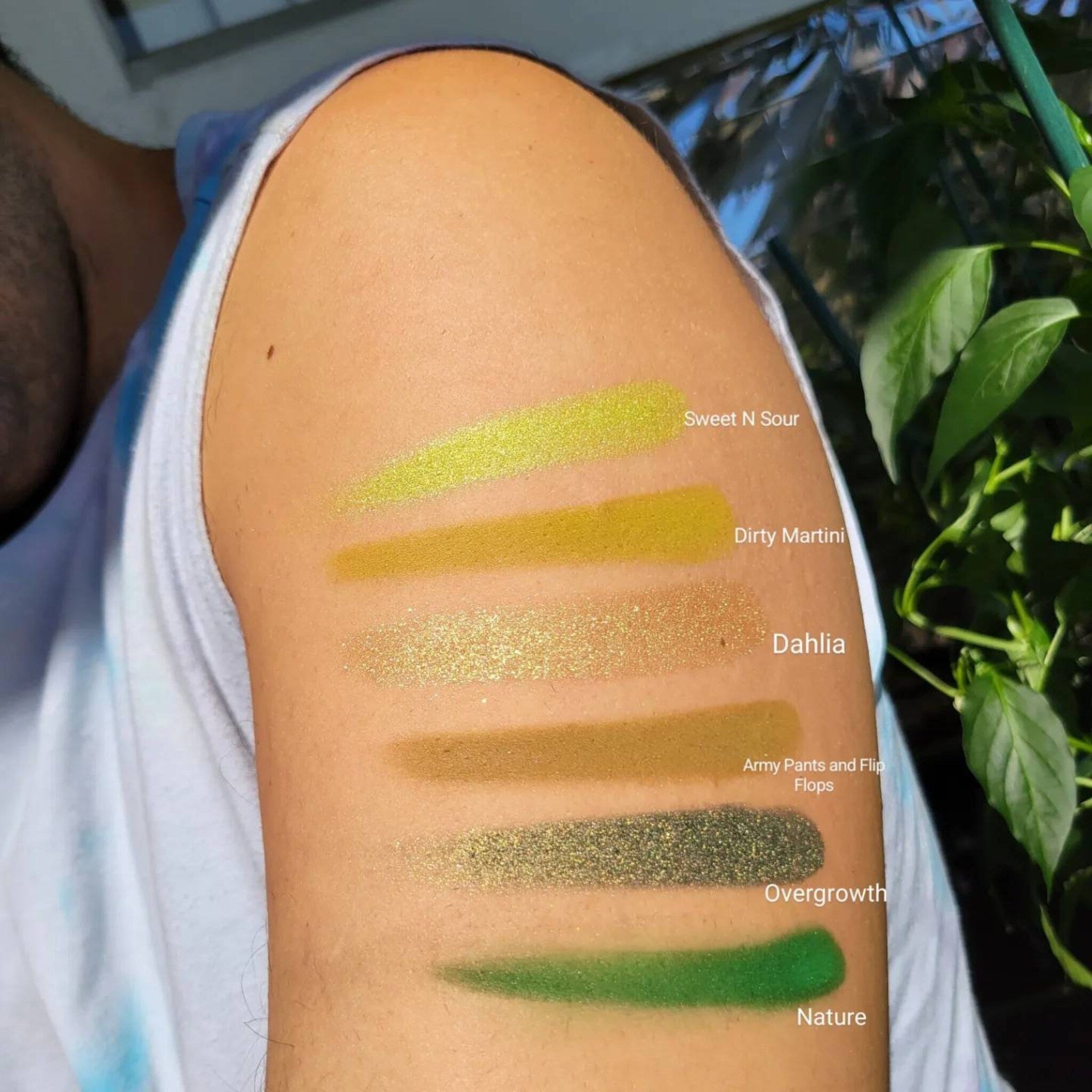 Hand applying emerald green eyeshadow with a fluffy brush onto eyelid, showcasing pigment intensity