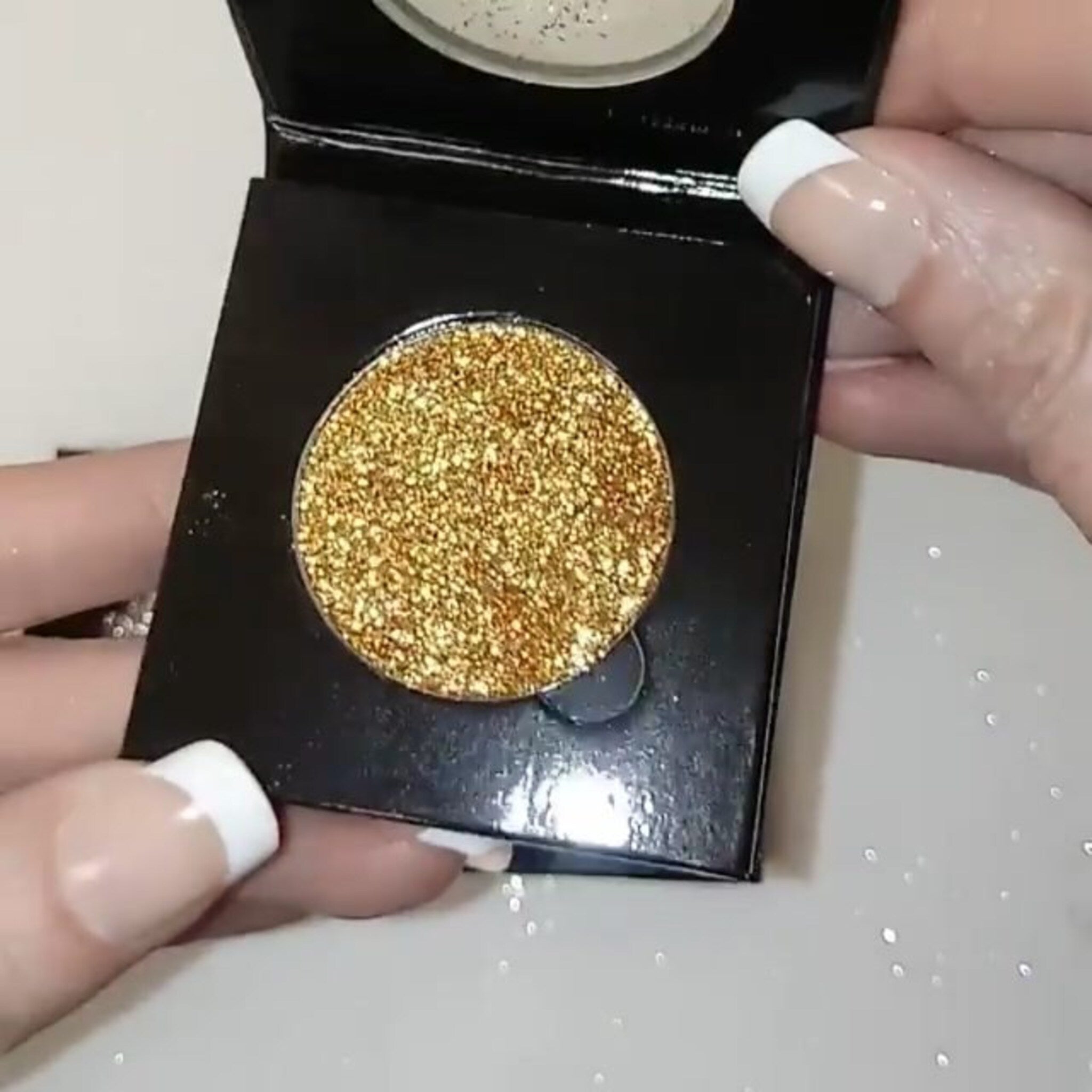 Close-up of golden pressed glitter eyeshadow with intense metallic shimmer and smooth texture