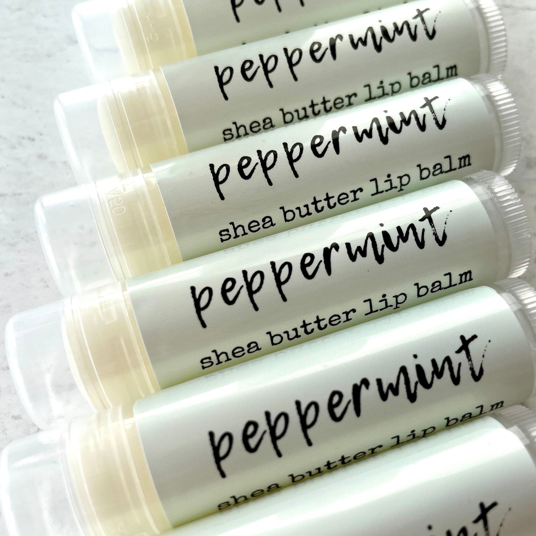 Peppermint lip balm tubes with white and clear packaging, black text labels