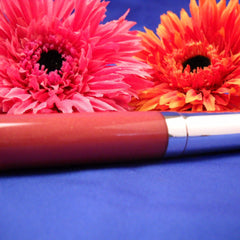 Lipstick tube with pink and orange flowers on blue background, metallic tube, glossy finish