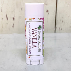 Lip balm tube with white and floral label, "Green Daffodil" and "Vanilla" text visible