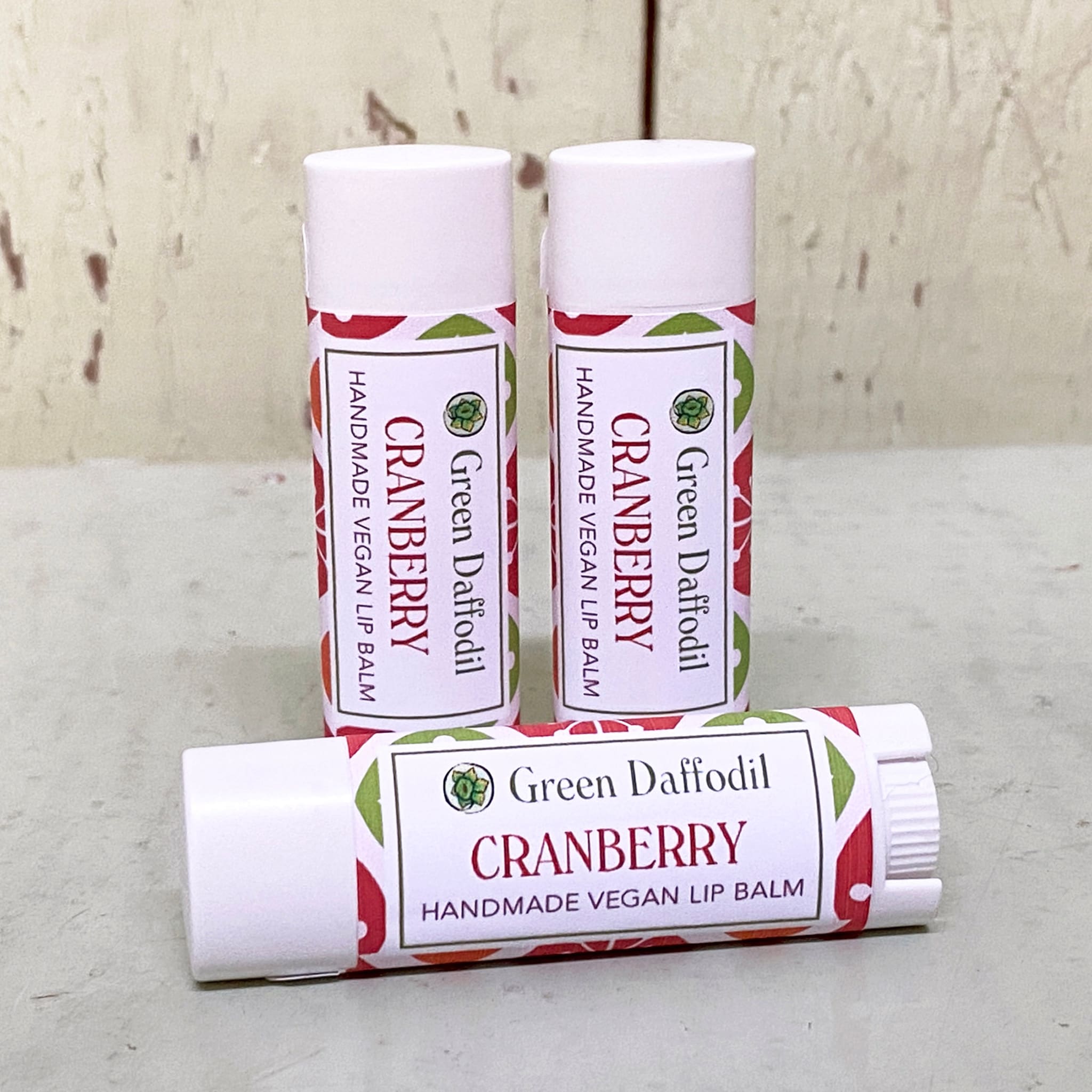 Lip balm tubes, white with red and green pattern, Green Daffodil branding visible