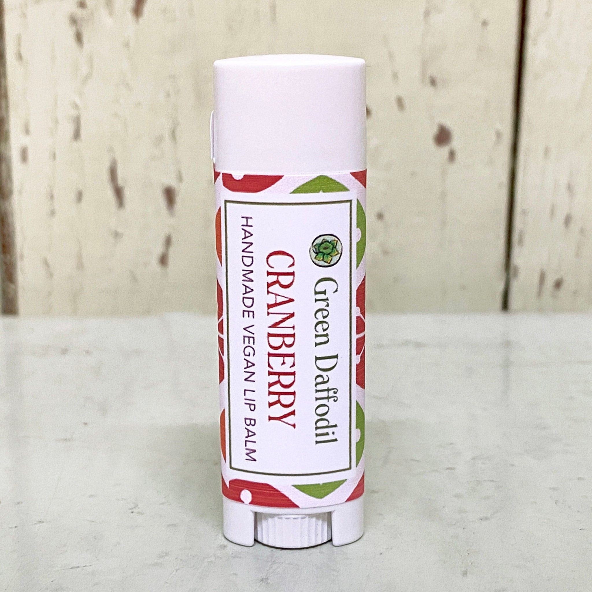 Lip balm tube, white and red patterned, with Green Daffodil branding and cranberry text