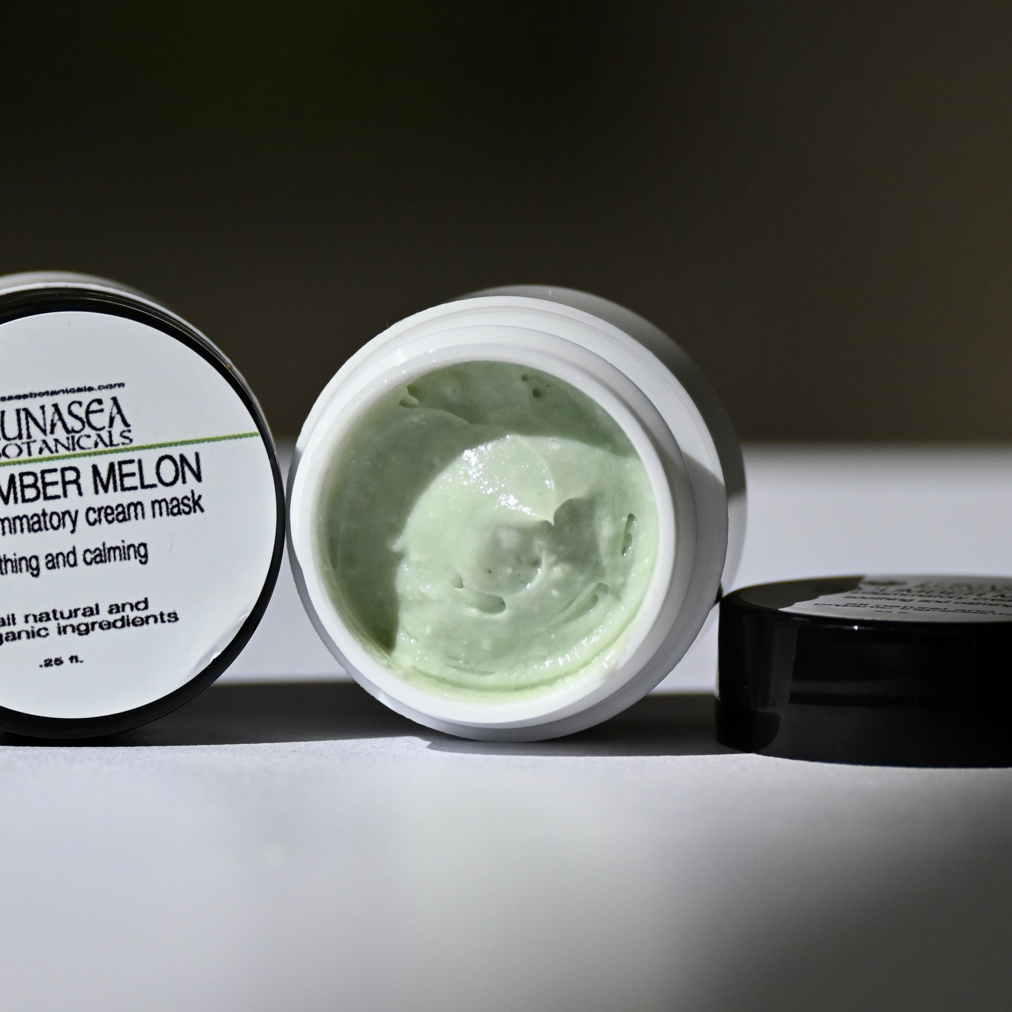 Cream mask with green color, white jar, and black lid, with brand name visible