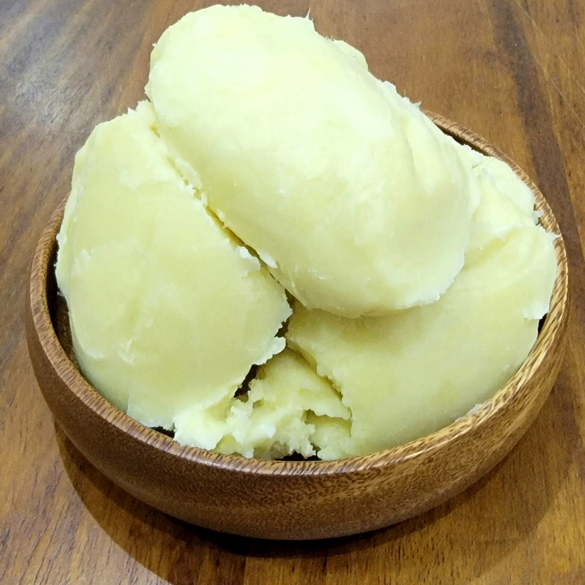 Golden unrefined shea butter in a sleek black jar with minimalist white label, showcasing rich creamy texture