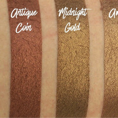 Hand applying amber brown shimmer eyeshadow with a brush, showcasing rich pigment and metallic finish