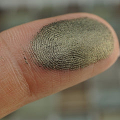 Close-up of army green shimmer pressed pigment in round pan with metallic sparkle
