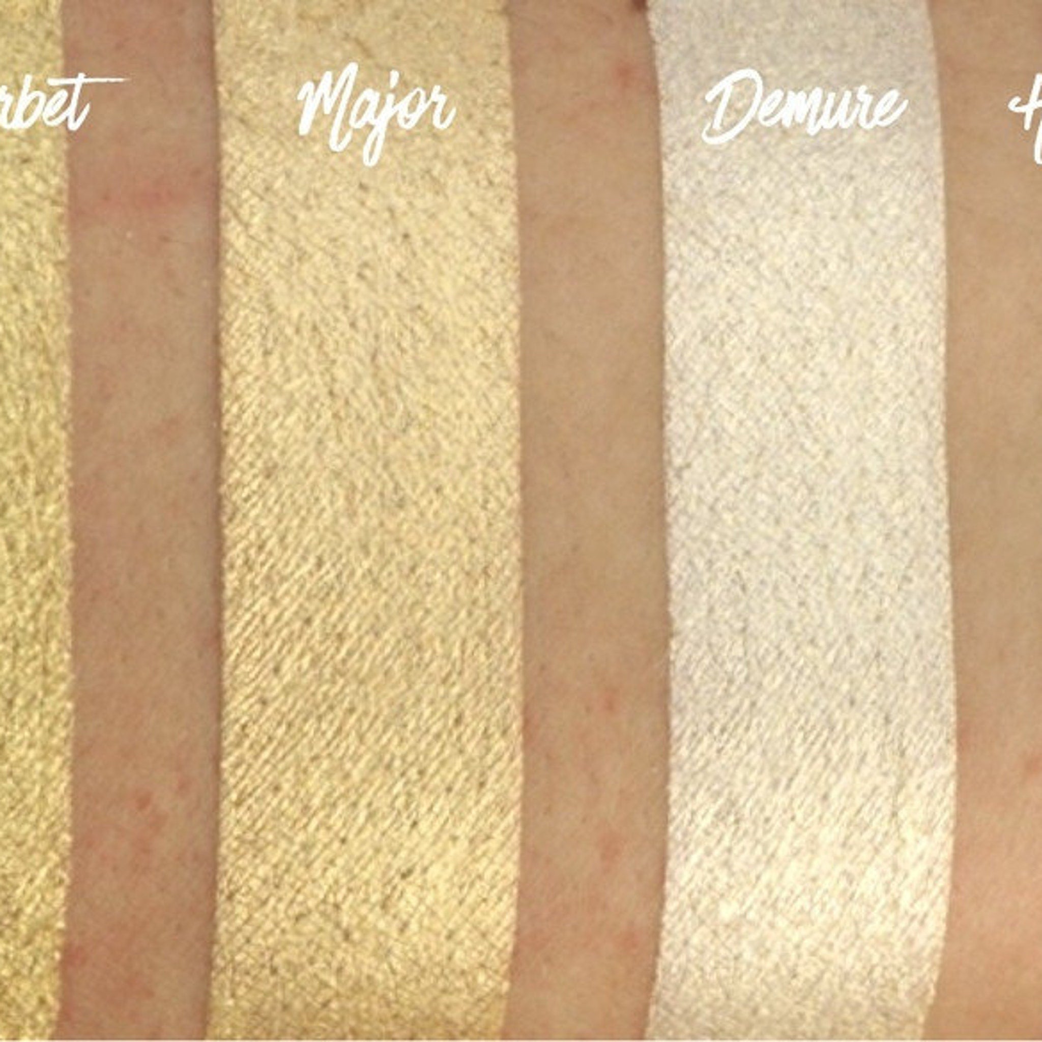 Hand applying light gold shimmer eyeshadow with fingertip to eyelid for a metallic finish