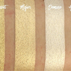 Hand applying light gold shimmer eyeshadow with fingertip to eyelid for a metallic finish