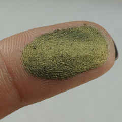 Side angle view of pearlescent green shimmer eyeshadow pan with reflective metallic finish
