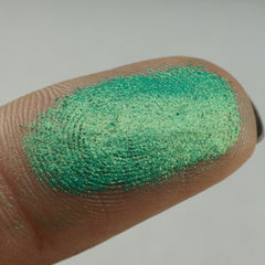 Side view of shimmering green and blue chrome pressed pigment duo showing metallic finish and compact size
