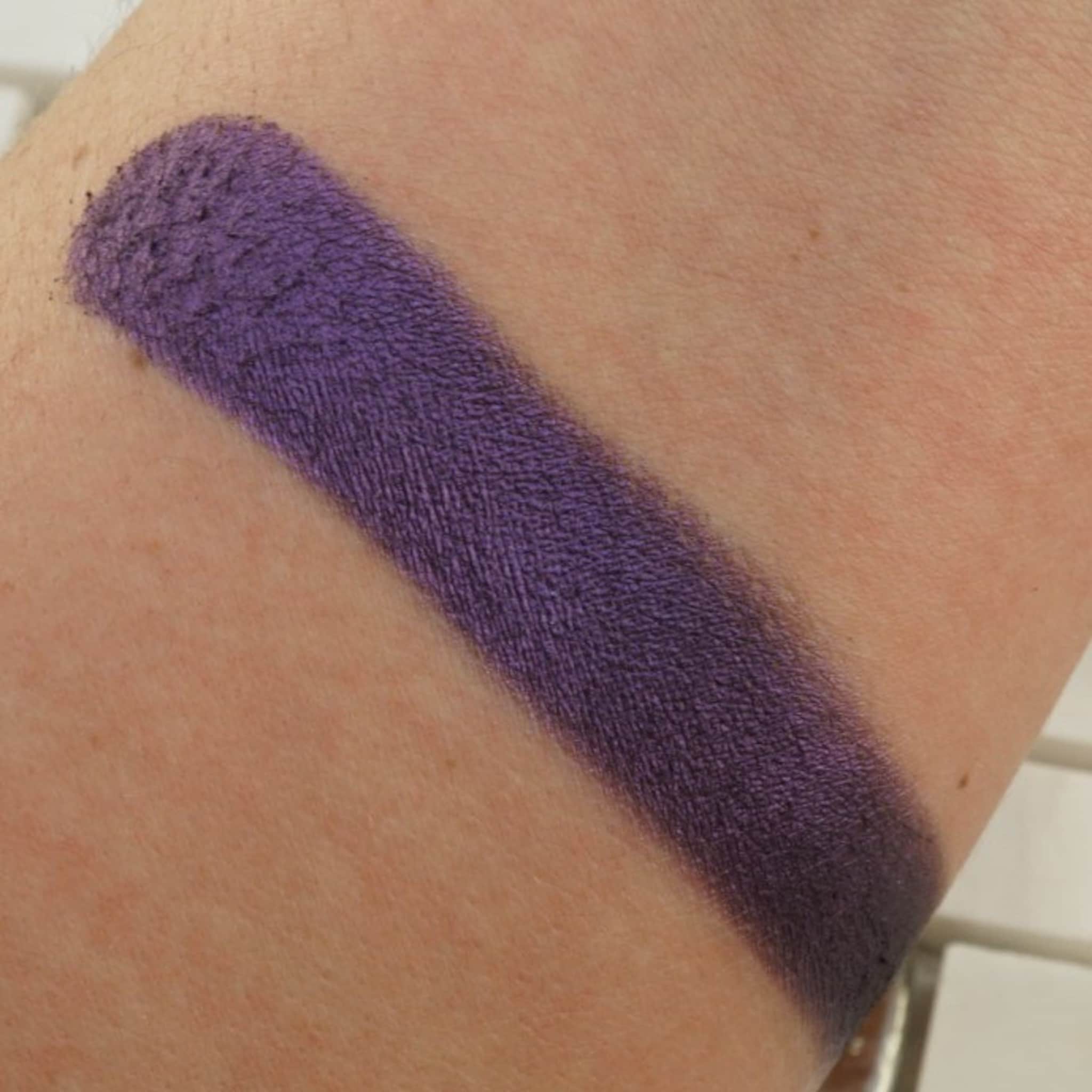 Purple eyeshadow swatch on arm, matte finish, textured appearance, for makeup application