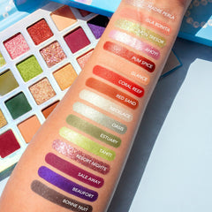 Close-up of makeup brush applying shimmery champagne eye shadow from palette to eyelid