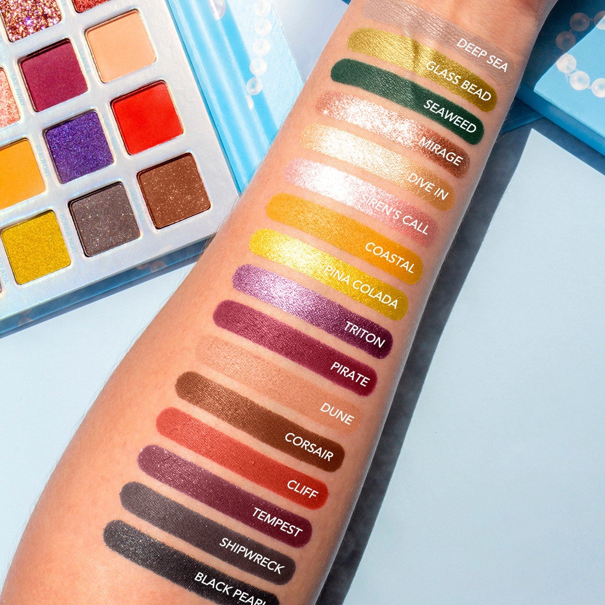 Open Pearl Paradise eyeshadow palette displaying 32 shimmer and matte shades in a sleek black case with gold trim