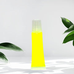 Lip gloss tube, yellow liquid, clear plastic tube, green leaves in background