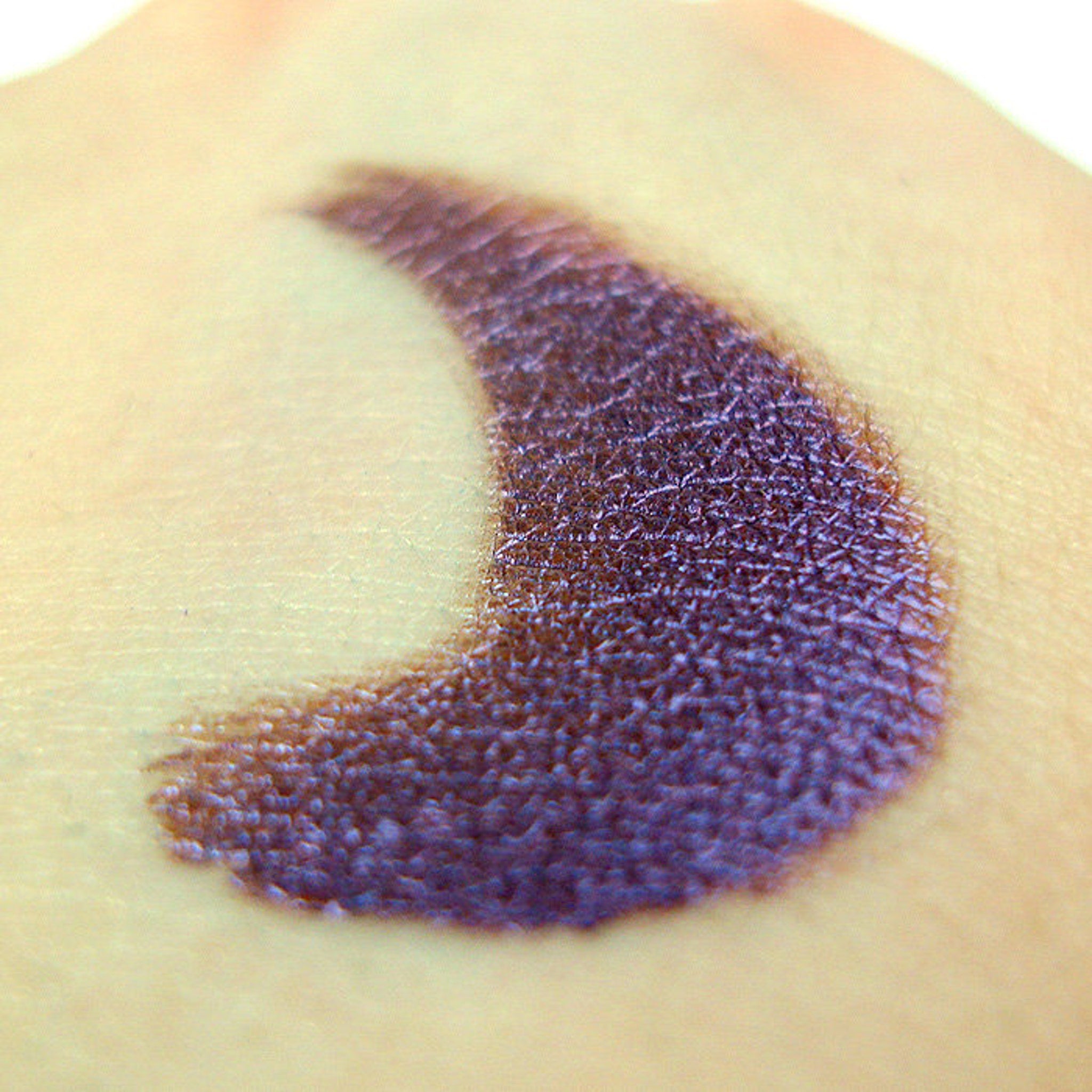 Close-up of shimmering Hotaru mineral eye shadow with iridescent flecks in a pressed powder compact