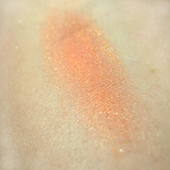 Side view of peach mineral eye shadow compact showing textured powder surface and sleek black case