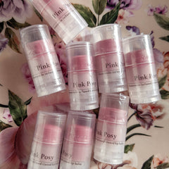 Tinted lip balm tubes with pink color, clear plastic, and Pink Posy label on floral background