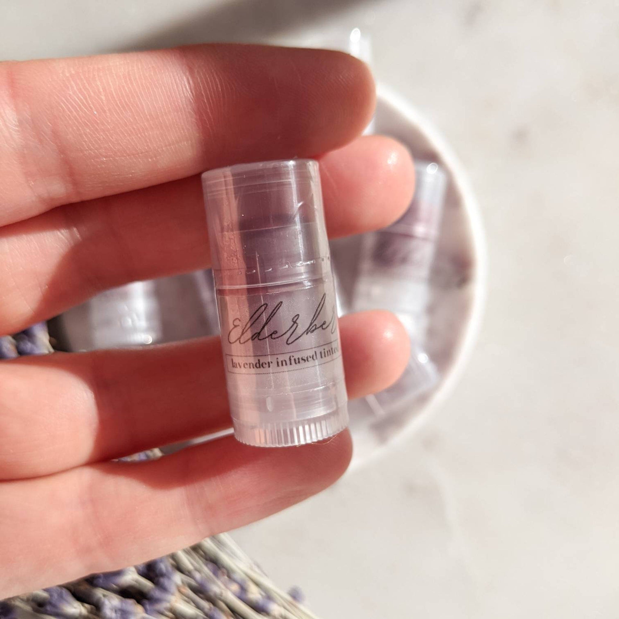 Lip tint in clear plastic tube with Elderber label, held in hand