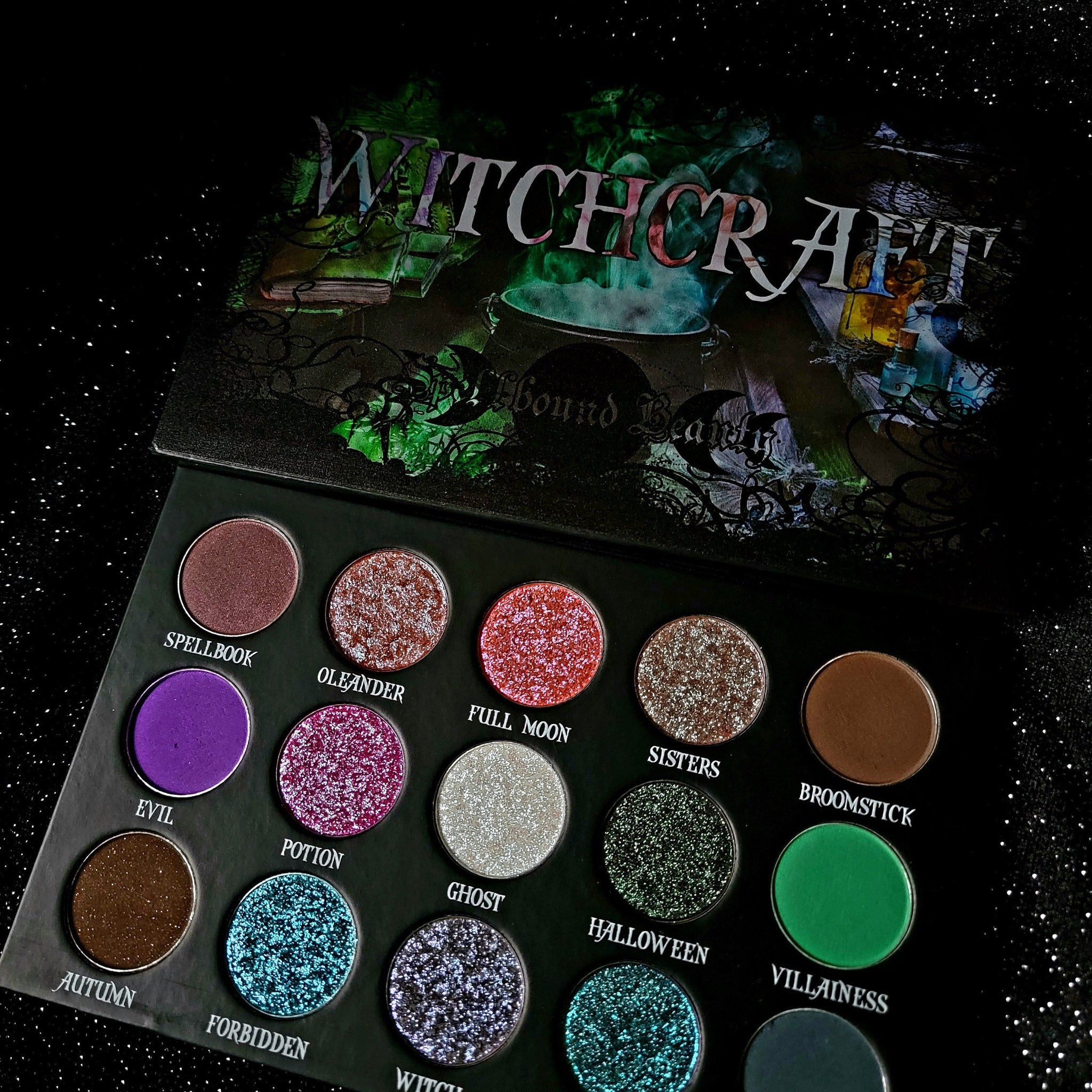 Eyeshadow palette with multiple colors, glitter, and Spellbound Beauty brand name on black background