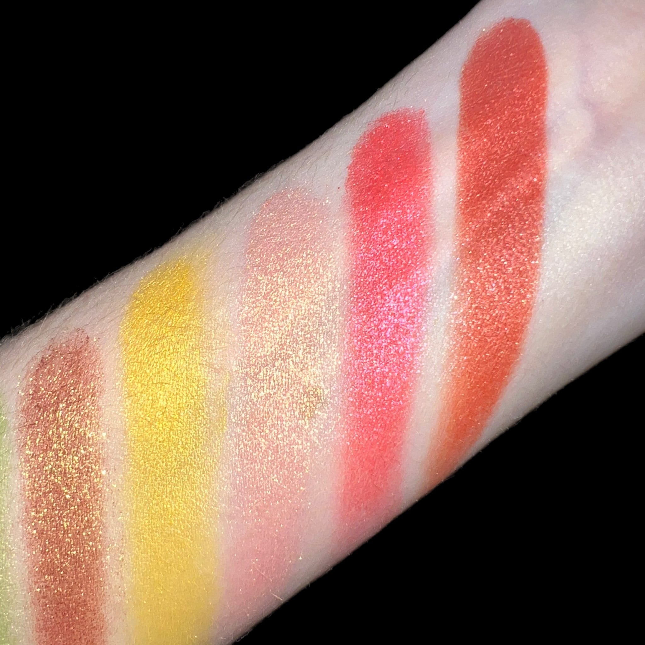 Eyeshadow swatches with various colors including yellow, pink, and orange on skin, showing shimmer