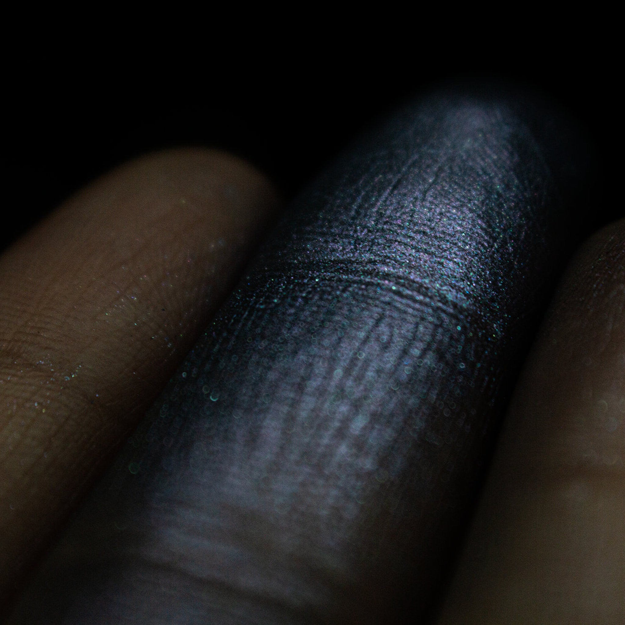 Close-up of duochrome eyeshadow pan showing grungy blue to purple shimmer shift in natural light