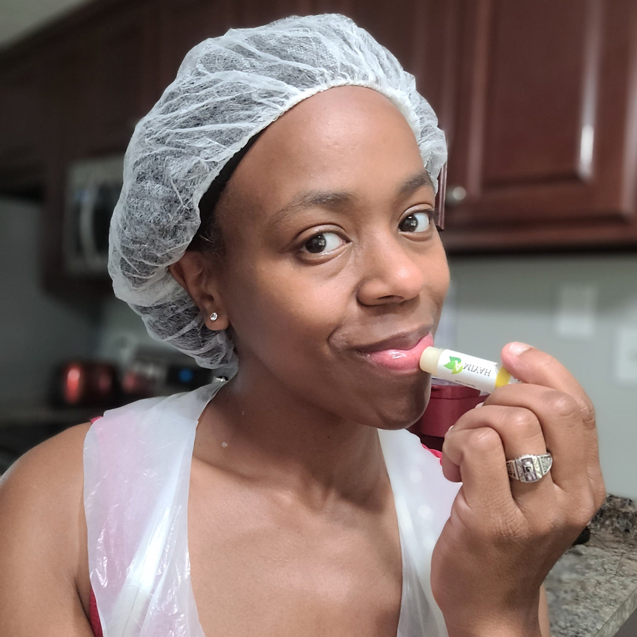 Lip balm application with yellow and white tube, woman wearing hair net and clear apron