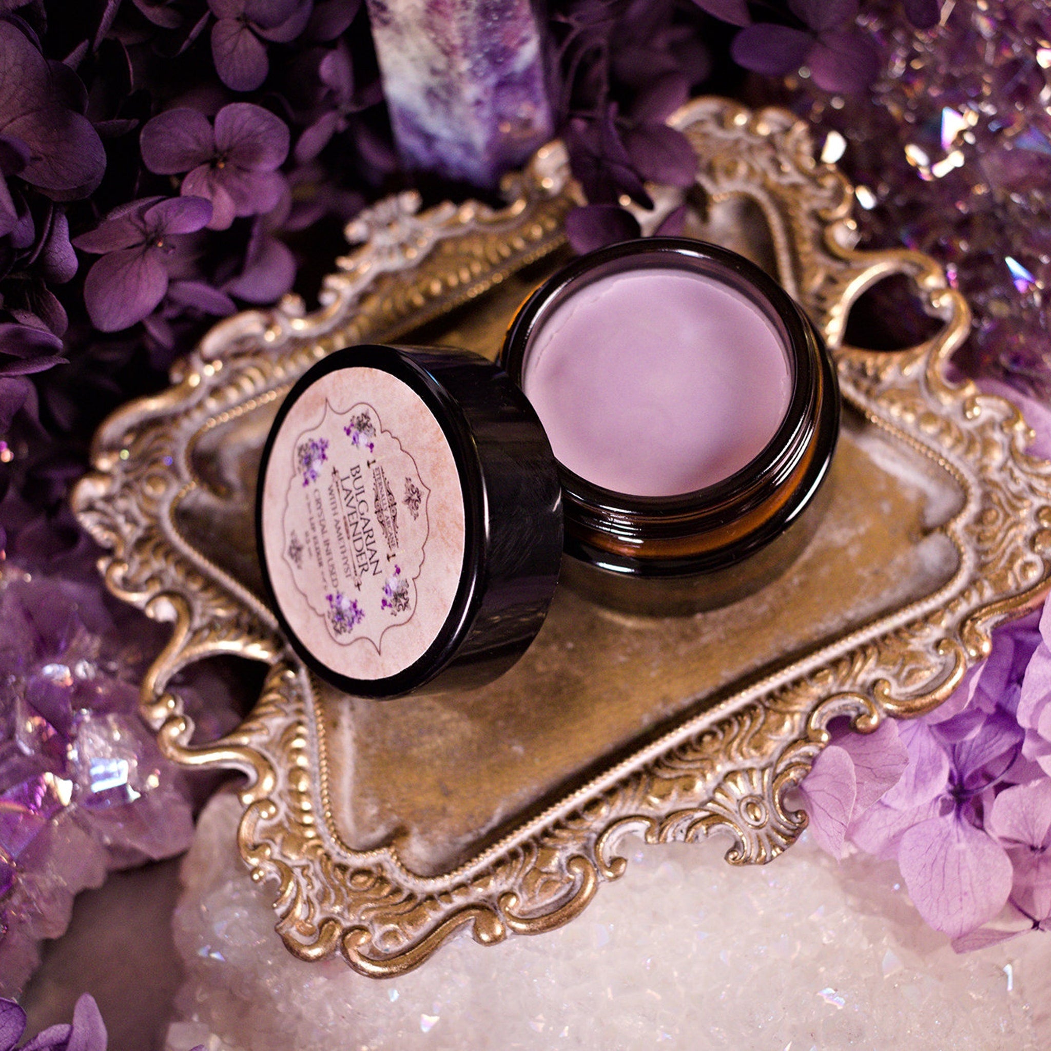 Lip balm jar with light purple balm, black rim, and Witch Beauty label on ornate gold tray