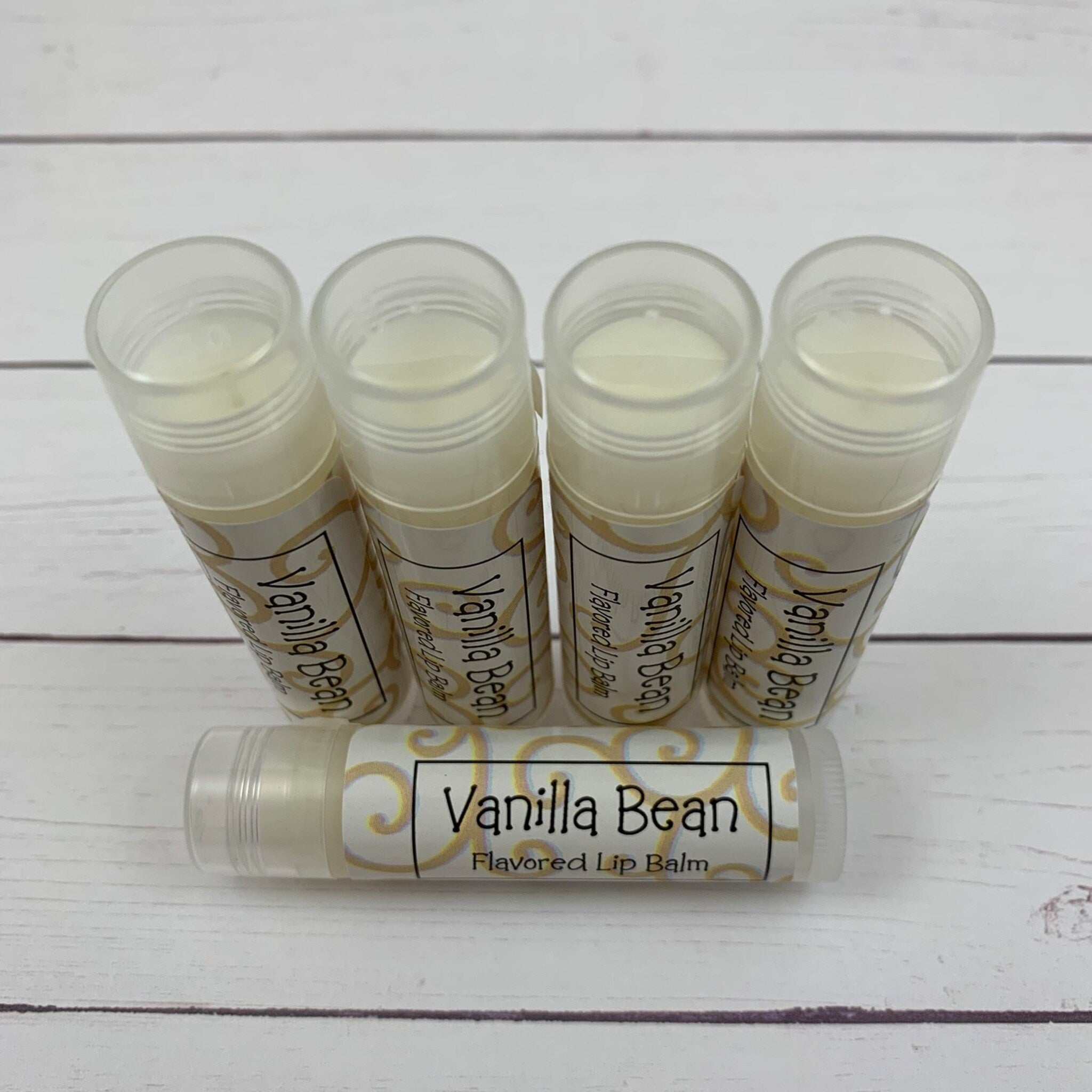 Lip balm tubes with white and gold labels, clear plastic tube, and creamy balm inside