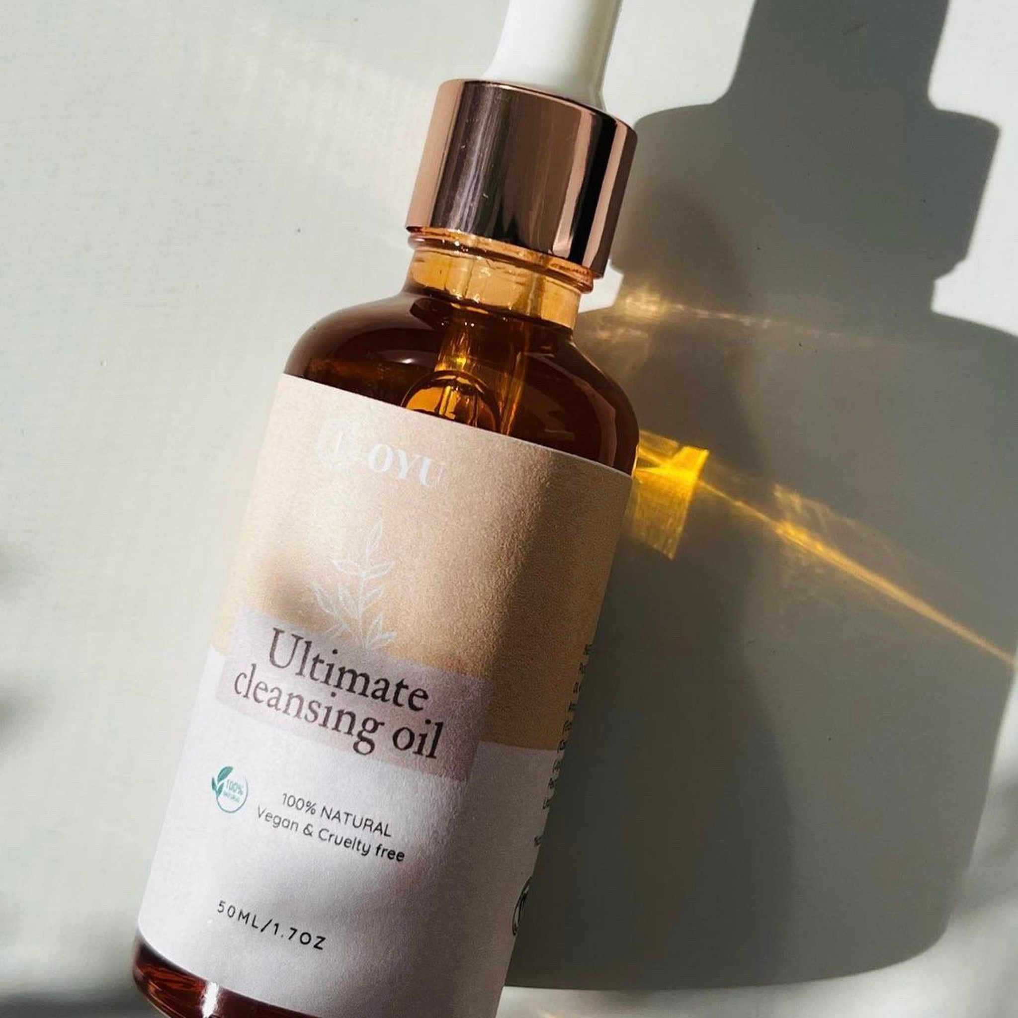 Face oil cleanser bottle, amber glass, rose gold cap, OYU label visible