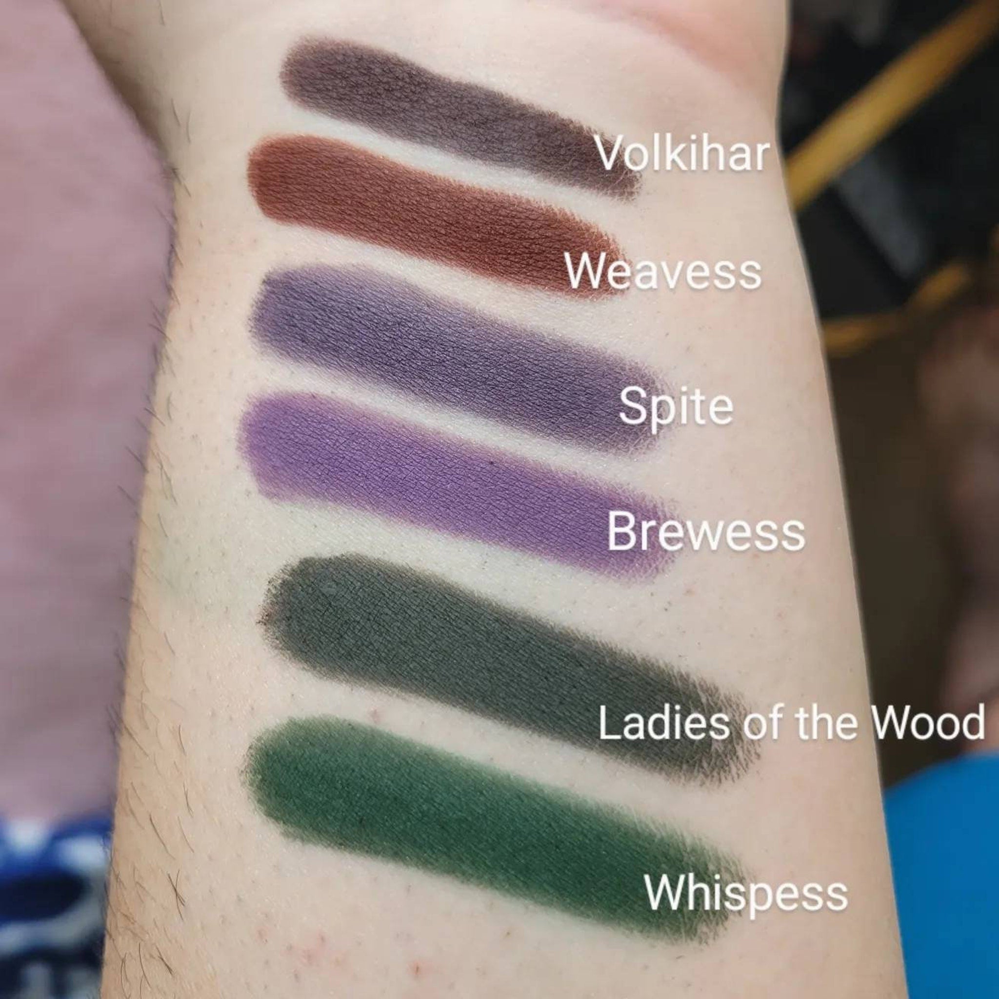 Eyeshadow swatches in various colors, including brown, purple, and green, on skin, with text labels