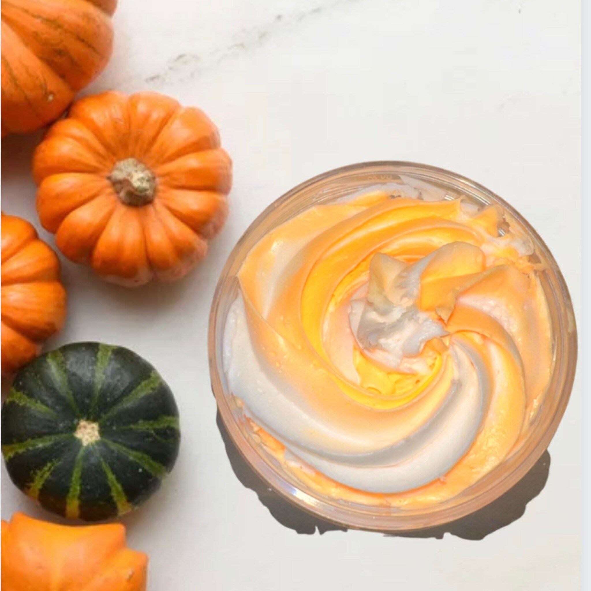 Close-up of whipped vanilla pumpkin body butter with airy texture in a white jar, showcasing its rich, creamy consistency