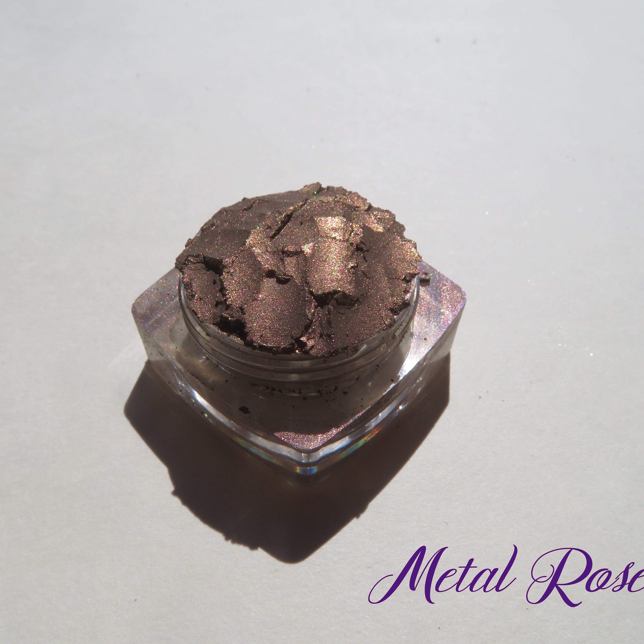 Side view of loose mineral eyeshadow powder in dark brown with shimmering rose metal finish, vegan and talc-free