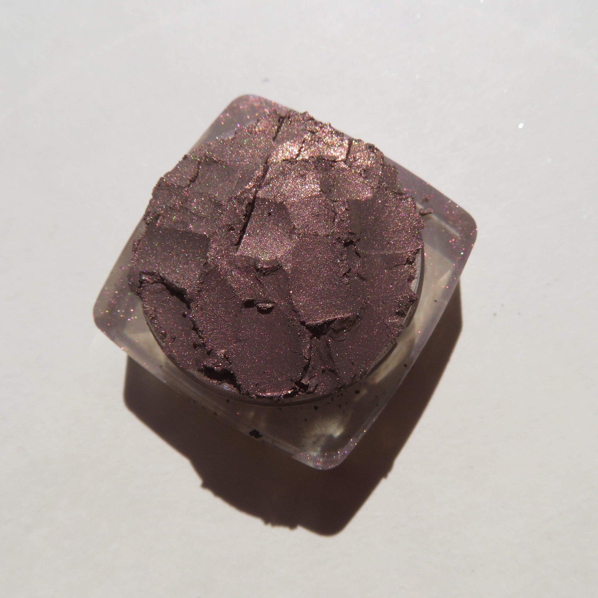 Side view of loose mineral eyeshadow in dark brown with shimmering rose metal finish, vegan and cruelty-free