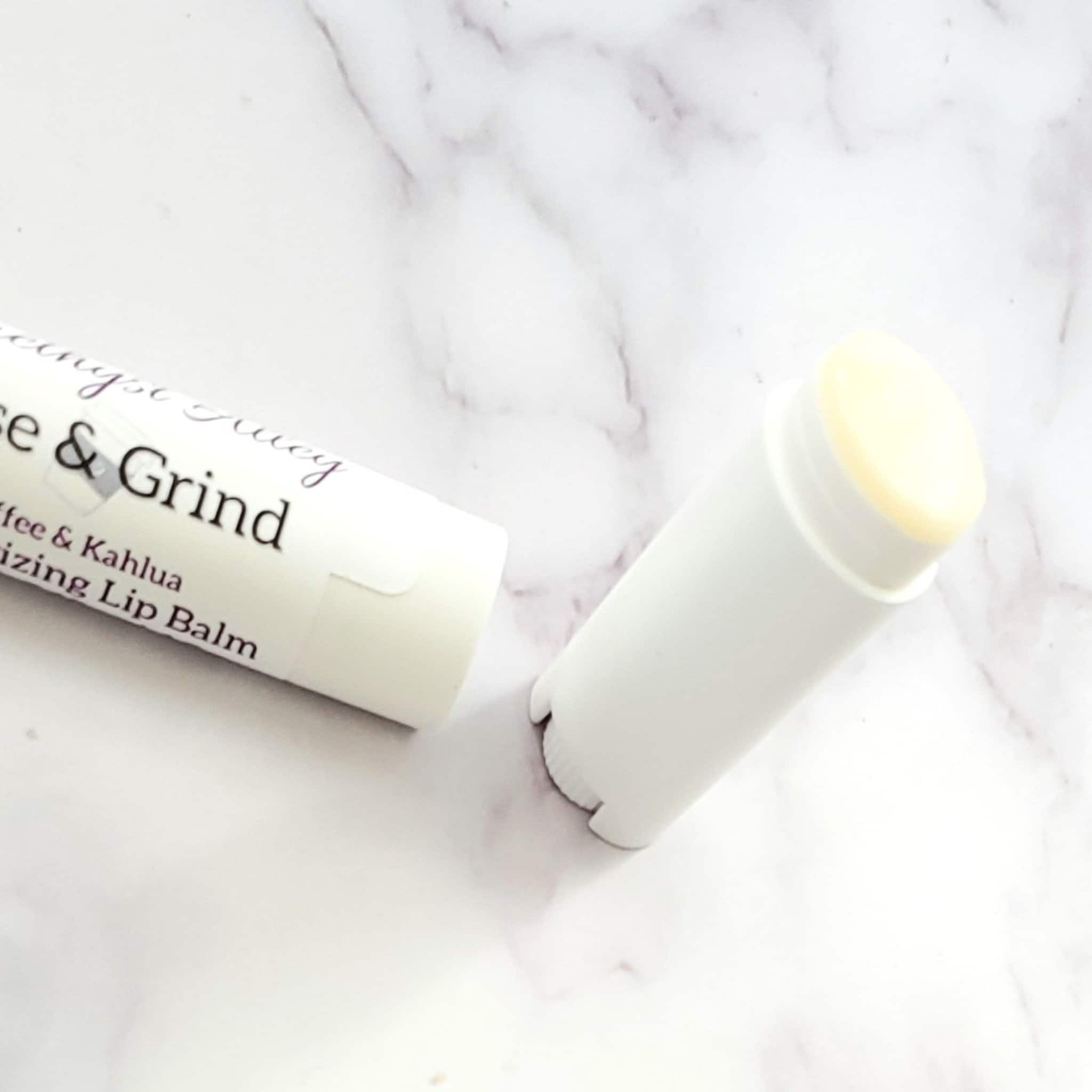Lip balm in white tube with visible text, light yellow balm, on marble surface