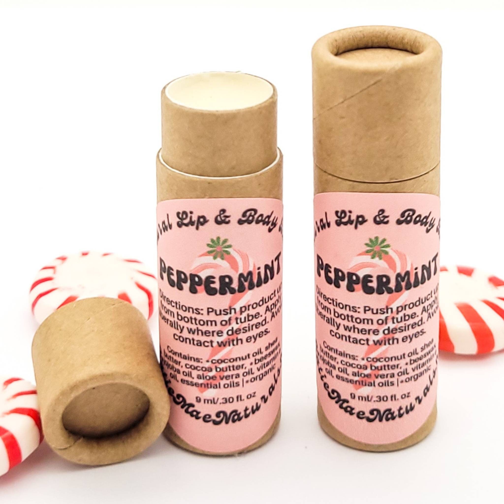 Lip balm tubes with pink labels, brown cardboard tubes, and peppermint candies around them. Mae Naturals brand.