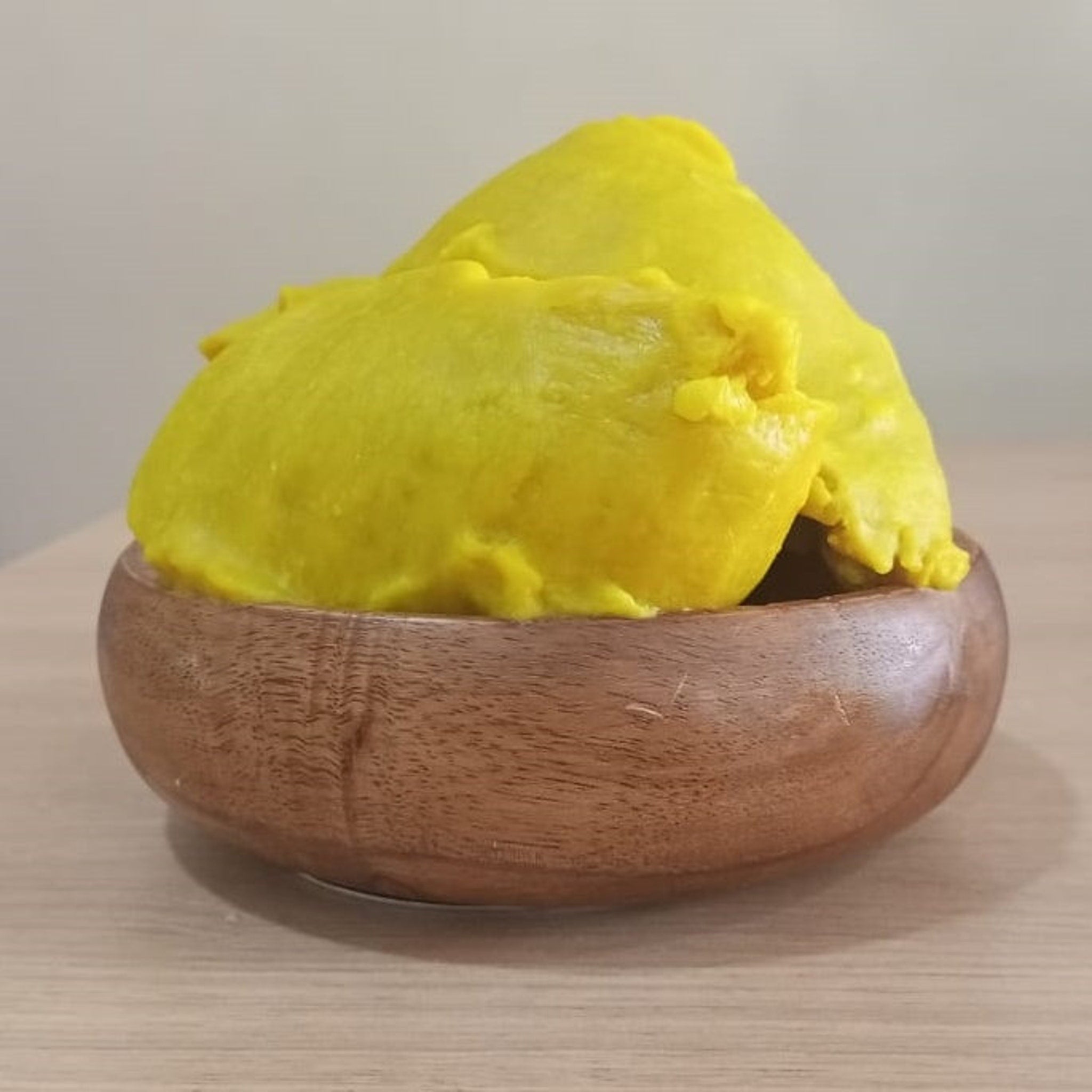 Yellow food in wooden bowl, smooth texture, brown wood bowl, on table