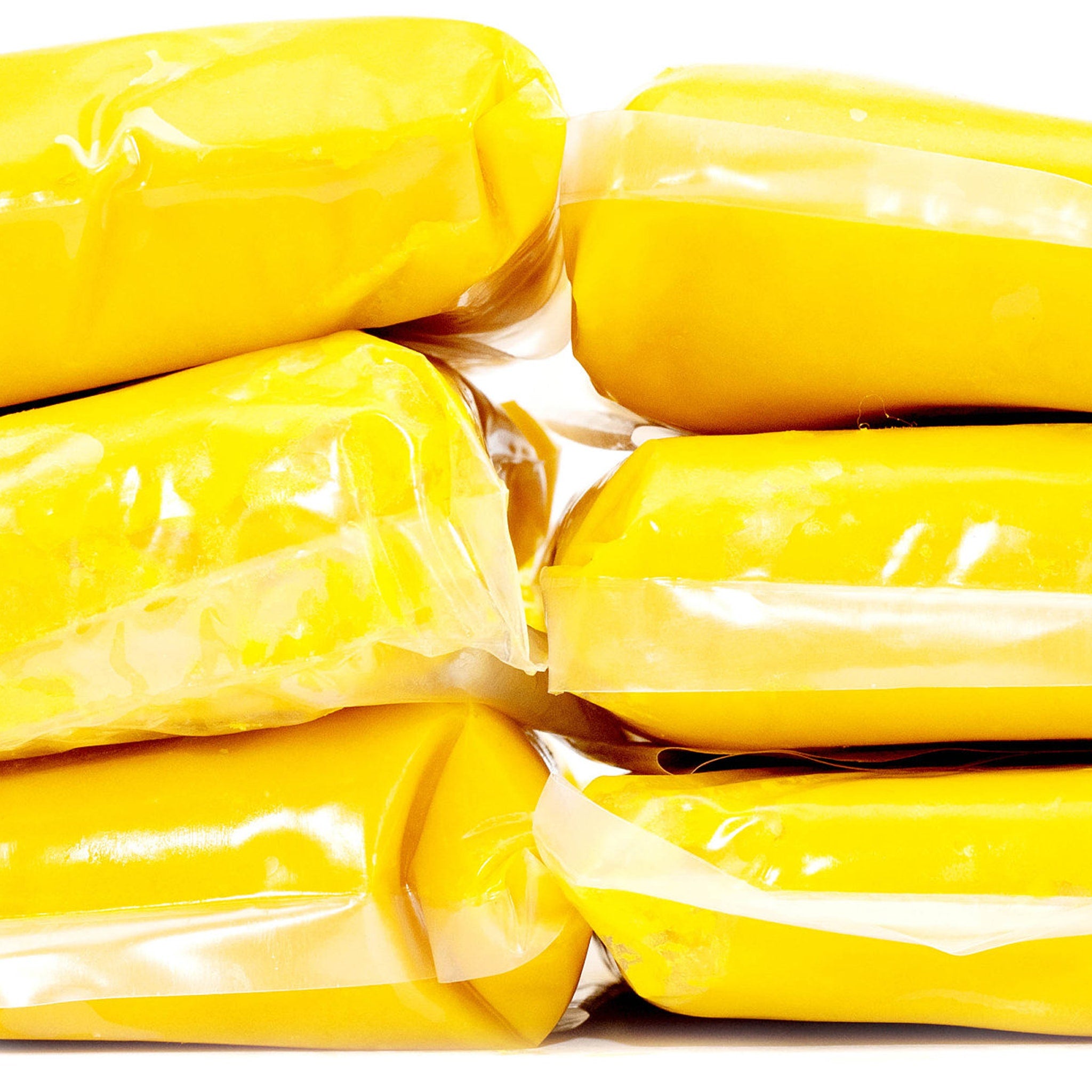 Yellow food items wrapped in clear plastic packaging, stacked together on white background.