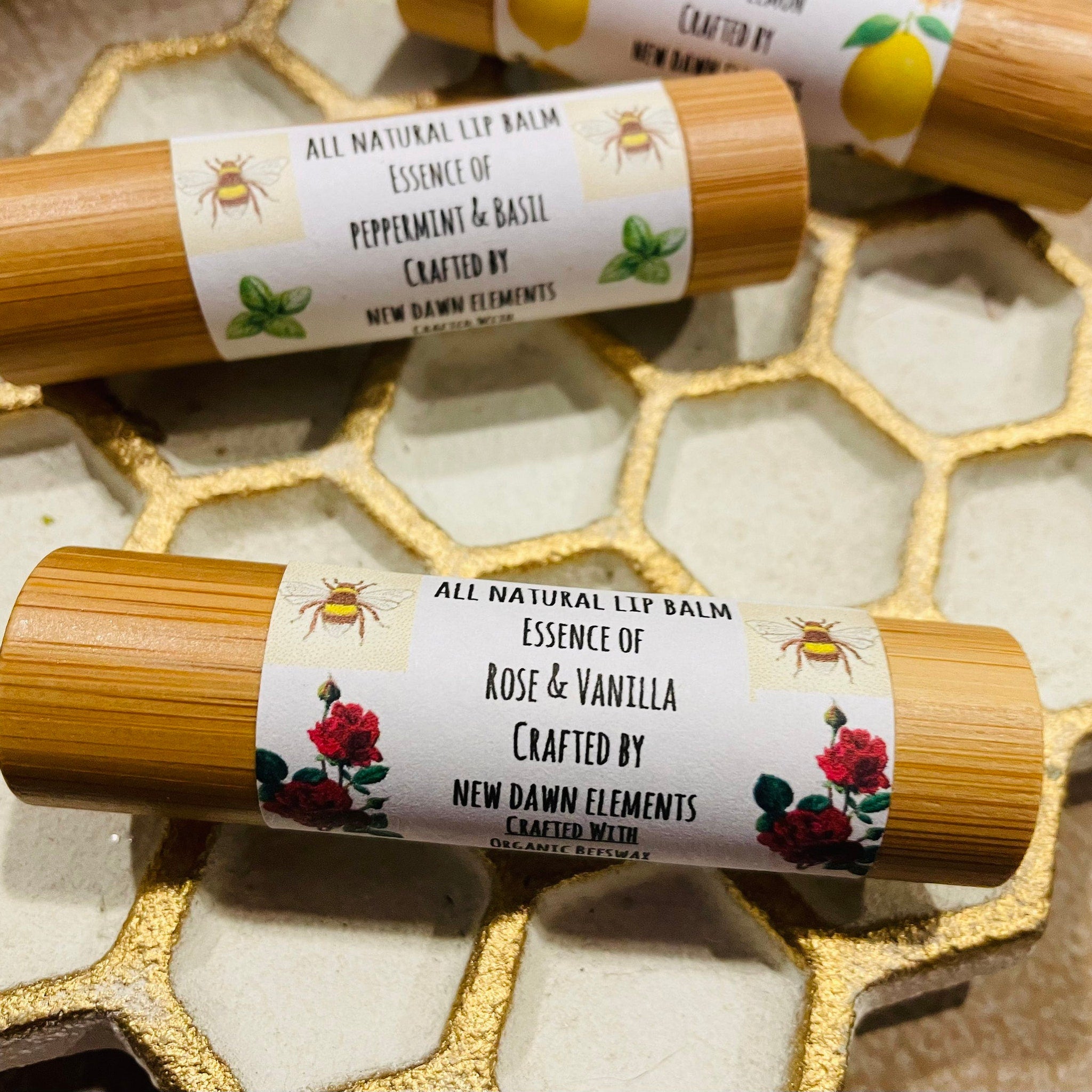Lip balm tubes with bamboo casing, white labels, and floral illustrations, New Dawn Elements