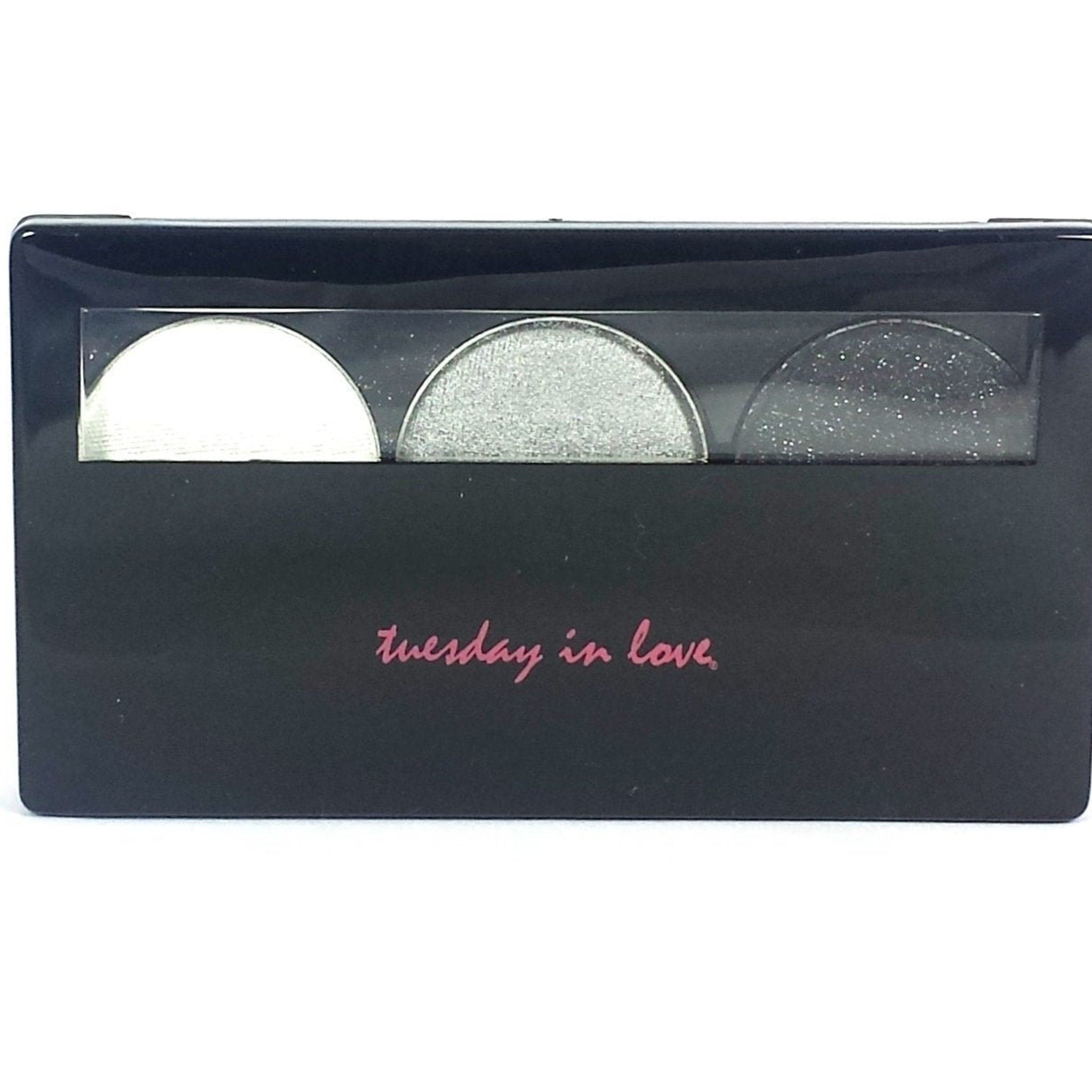 Close-up of three shimmery silver eyeshadow pans with varying metallic finishes in sleek black compact.