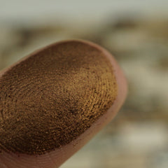 Side angle view of amber brown shimmer pressed pigment pan showcasing metallic finish and vegan compact size