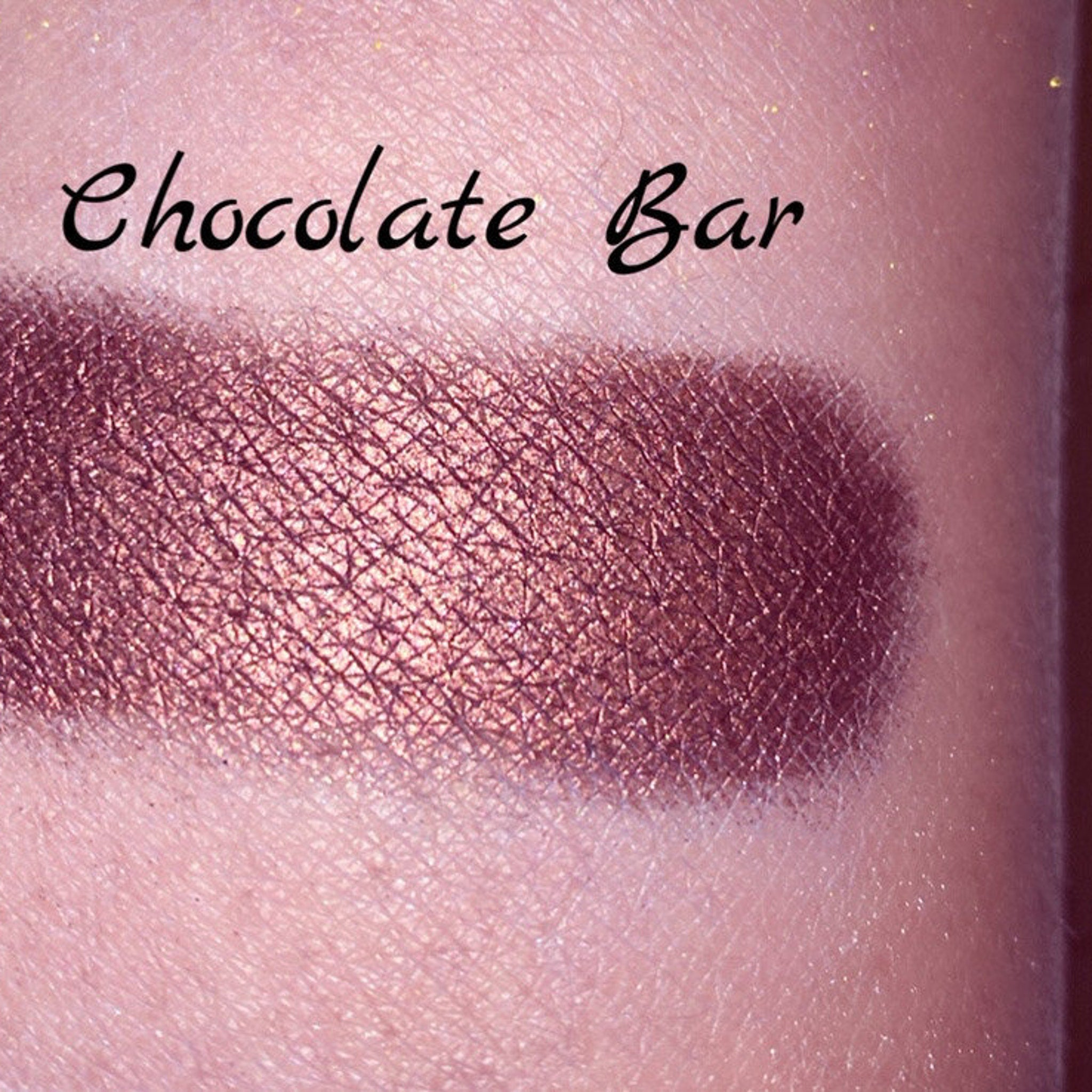 Top-down view of vegan chocolate brown shimmer eyeshadow pan with gold label on sleek black compact